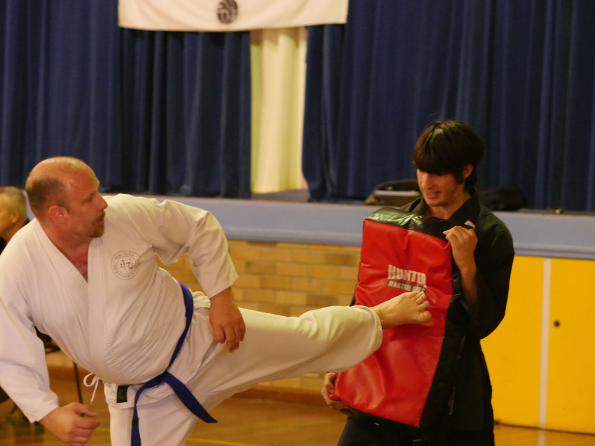 Brown belt martial artist side-kicking kick bag at grading